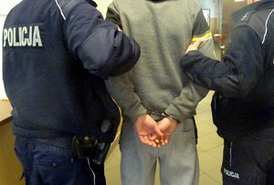 zatrzymany mężczyzna trzymany przez policjantów