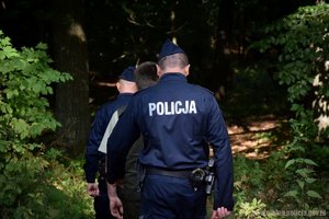 Policjanci idący przez las