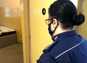 Policjantka stojąca przy otwartych drzwiach do celi
