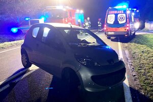 Rozbity samochód na drodze, a za nim służby ratunkowe