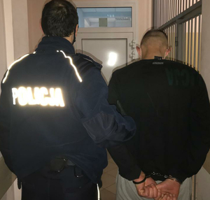 Umundurowany policjant prowadzi osobę zatrzymaną