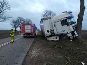 Samochód ciężarowy DAF uderzył w drzewo, z lewej strony stoi wóz strażacki i strażak