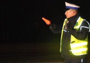 policjant stojący w porze nocnej, trzymając w ręku latarkę