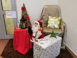 Na zdjęciu figurka mikołaja, fotel, stolik, prezent