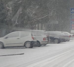 wzdłuż stoją zaśnieżone pojazdy