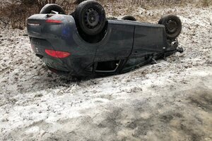Seat Leon na ośnieżonym poboczu drogi leżący na dachu, po tym jak wpadł w poślizg i wypadł z drogi.