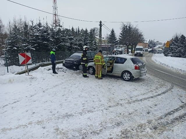 Przy płocie stoją dwa rozbite pojazdy przy nich strażacy