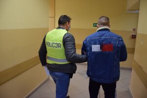 Zatrzymany mężczyzna prowadzony przez policjanta