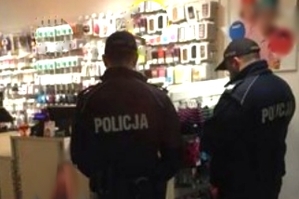 Dwóch umundurowanych policjantów stojących tyłem w sklepie