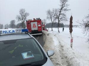 Na pierwszym planie radiowóz i wóz strażacki, dalej  po prawej stronie samochód w rowie