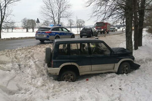 Na zdjęciu na poboczu widać pojazd który uderzył w drzewo, na drodze stoją służby ratownicze