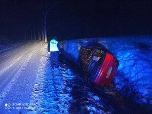 po prawej stronie w rowie na boku leży samochód po lewej stoi policjant