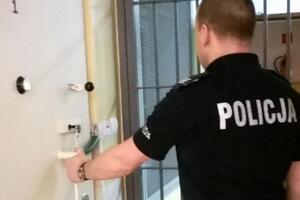 Policjant stojący przed kratą drzwi