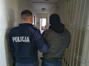 Policjant prowadzi osobę zatrzymaną