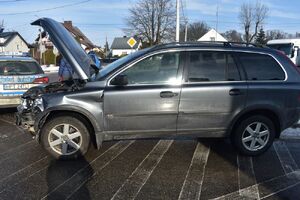 Uszkodzony samochód osobowy z otwartą pokrywą silnika z lewej strony radiowóz