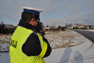 Policjant mierzy prędkość pojazdów urządzeniem