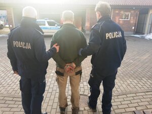 dwóch policjantów prowadzi osobę zatrzymaną