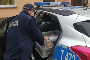Policjant wyciągający skrzynkę z pączkami z radiowozu