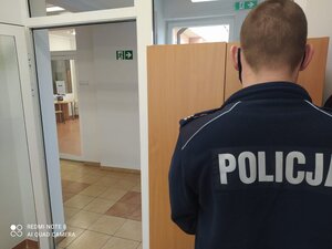 na zdjęciu policjant stoi przed szafą