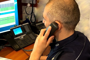 Oficer dyżurny odbiera telefon siedząc przed komputerem