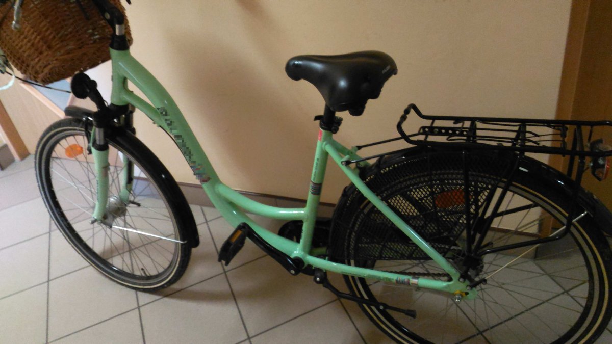 na zdjęciu zielony rower z koszykiem na ramie kierownicy