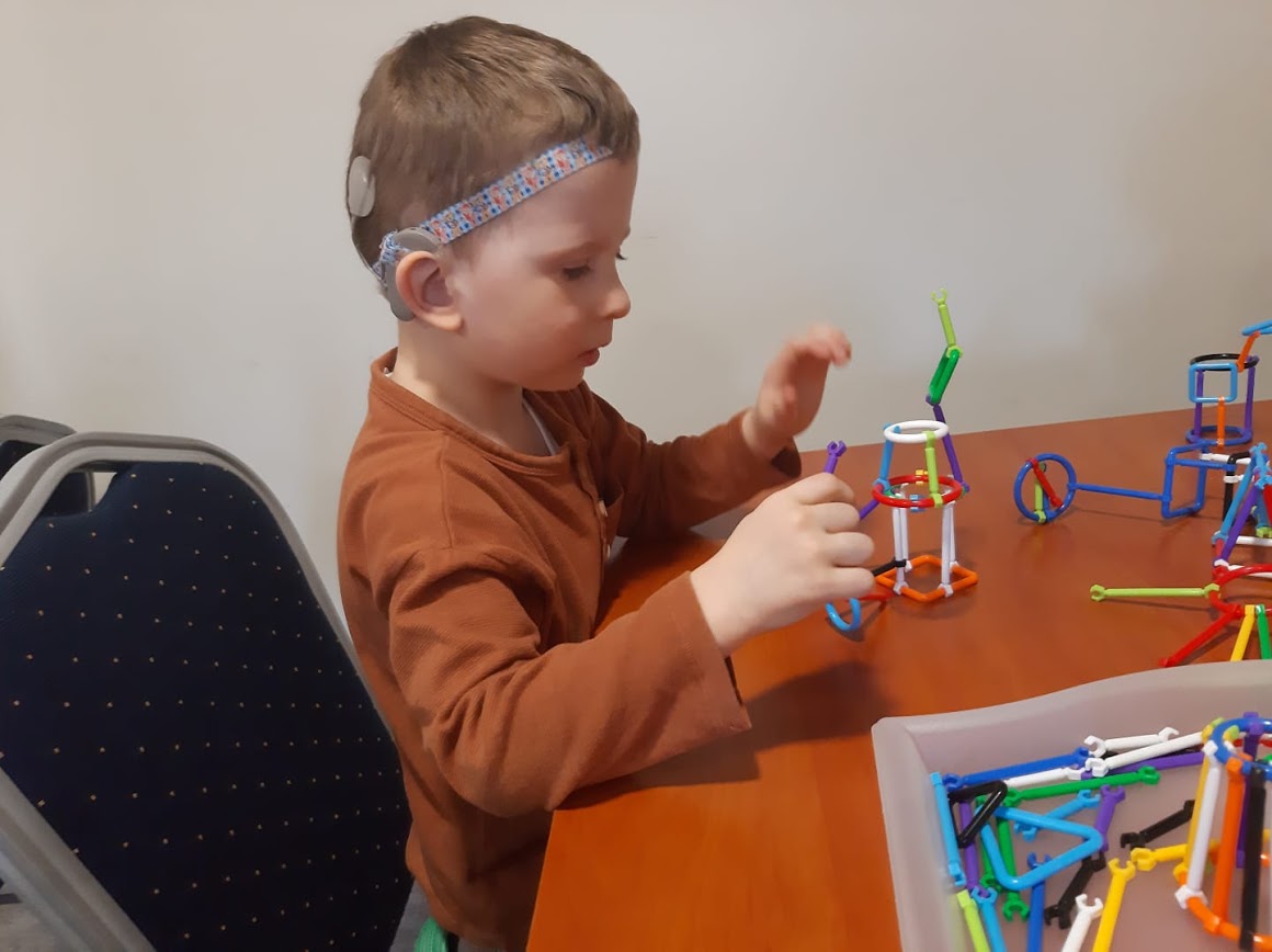 chłopiec siedzący przy stole i układa zabawki
