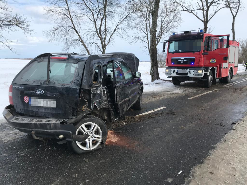 Na środku drogi stoi uszkodzony pojazd Kia przed nim wóz strażacki