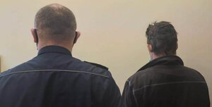 policjant prowadzi osobę zatrzymaną