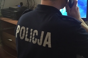Policjant siedzący przy stanowisku pracy ze słuchawką przy uchu
