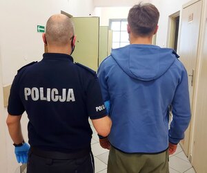 policjant prowadzi osobę zatrzymaną