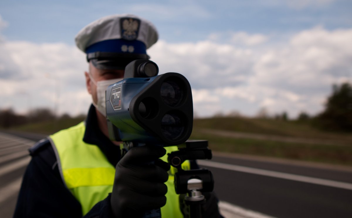 Policjant trzymający w ręku ręczny miernik prędkości
