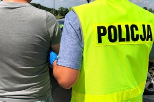 Policjant prowadzi osobę zatrzymaną