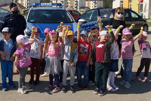 Przedszkolaki z odblaskami na rękach przy policyjnym radiowozie