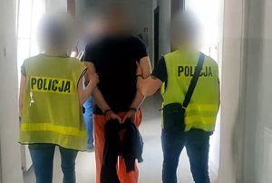 dwóch policjantów prowadzi osobę zatrzymaną