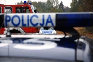 Dach policyjnego radiowozu i wóz strażacki w tle.
