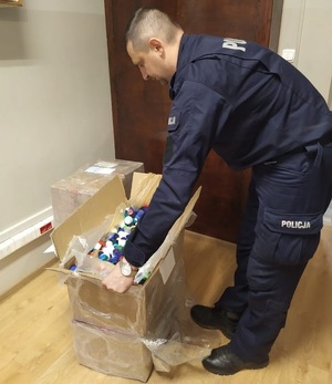 policjant otwiera karton z nakrętakmi