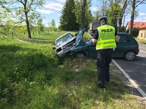 po lewej stronie policjant przed nim jeden pojazd bokiem do rowu, drugi w rowie