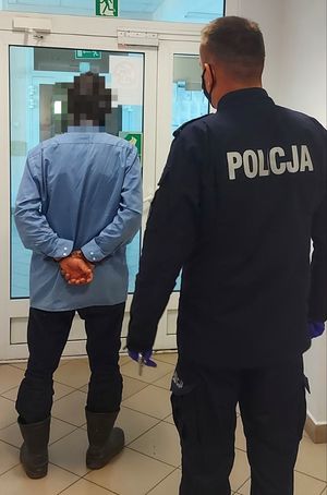 Policjant stoi za osobą zatrzymaną