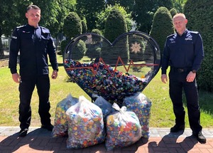 dwóch policjantów pomiędzy nimi worki z nakrętkami