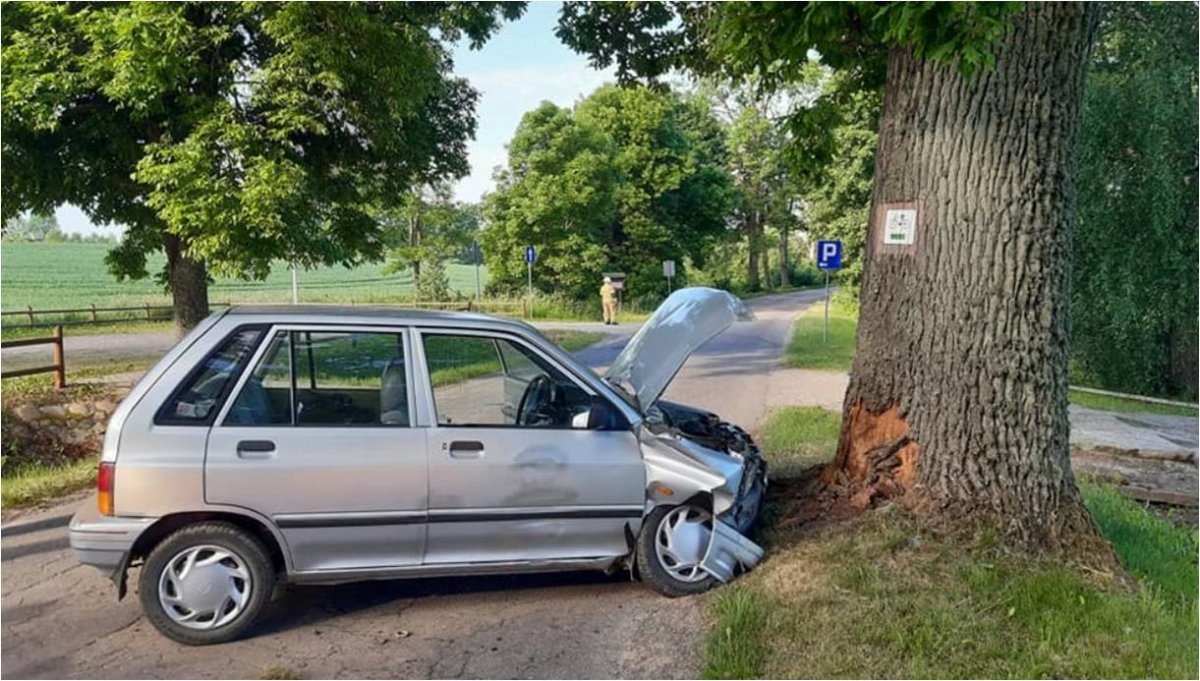 Pojazd osobowy z uniesioną pokrywą silnika stojący przed drzewem