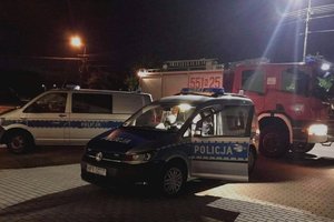 Policyjne radiowozy i wóz strażacki w nocy na parkingu