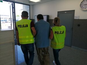 Policjanci prowadzą osobę zatrzymaną