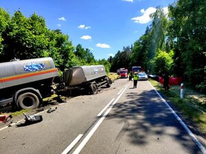 po lewej stronie na poboczu w rowie pojazd ciężarowy, w oddali na drodze służby ratunkowe