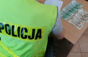 Policjant przelicza odzyskane pieniądze