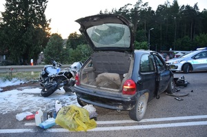 na drodze rozbity pojazd osobowy z uniesioną klapa od bagażnika, obok przewrócony motocykl