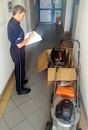 na korytarzu dwie kosiarki przy nich policjantka