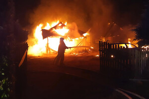 Płonący budynek i gaszący go strażak