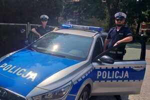 Policjanci z oleckiej drogówki stojący przy radiowozie