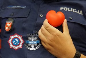 Dłoń trzymająca przedmiot w kształcie serca na tle policyjnej koszuli