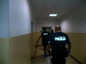 policjant prowadzi osobę zatrzymaną